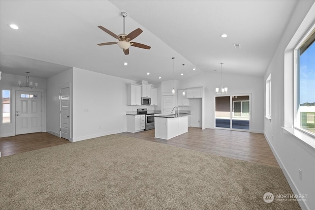 unfurnished living room featuring ceiling fan with notable chandelier, light wood-type flooring, lofted ceiling, and sink