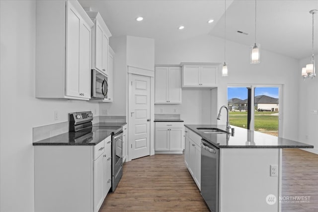 kitchen with an island with sink, appliances with stainless steel finishes, hanging light fixtures, and sink