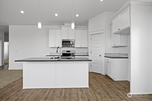 kitchen with white cabinets, an island with sink, appliances with stainless steel finishes, and hanging light fixtures