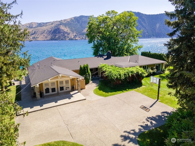 view of front of house featuring a patio, a water and mountain view, and a front lawn