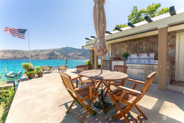 view of patio / terrace featuring area for grilling, an outdoor kitchen, and a water and mountain view