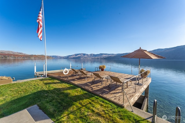 dock area featuring a water and mountain view and a lawn