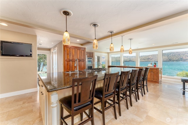 kitchen with dark stone counters, a large island with sink, pendant lighting, and a kitchen breakfast bar