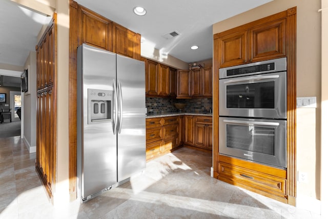 kitchen featuring decorative backsplash, stainless steel appliances, and light tile patterned floors