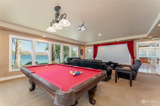 recreation room featuring light colored carpet, a water view, a tray ceiling, and billiards