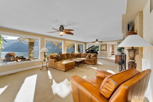 carpeted living room with a water view and ceiling fan