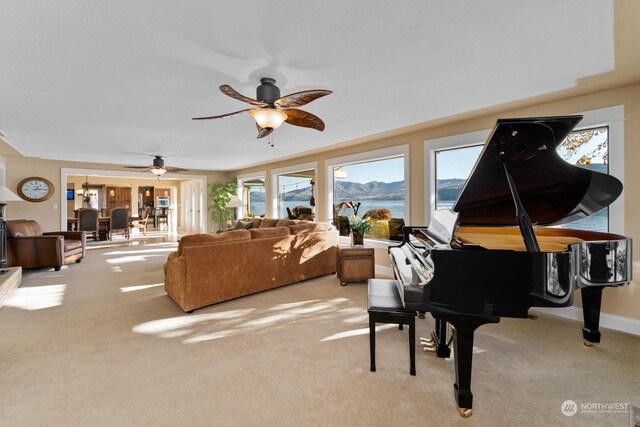 living room with a water view, light carpet, and ceiling fan