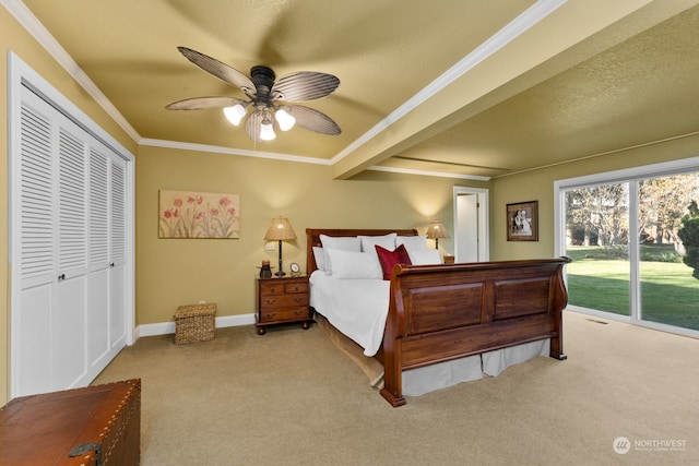 carpeted bedroom featuring ornamental molding, a closet, beam ceiling, and ceiling fan