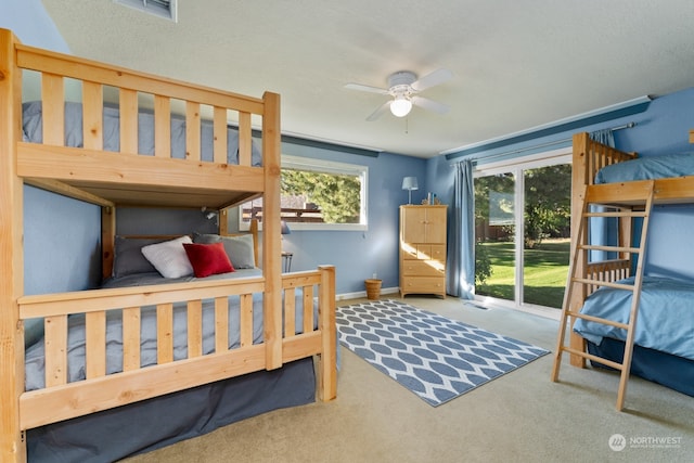 carpeted bedroom with multiple windows, access to exterior, and ceiling fan