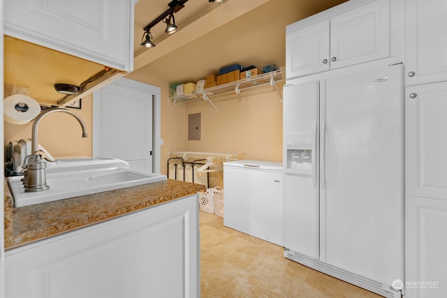 clothes washing area with electric panel, sink, track lighting, and light tile patterned floors