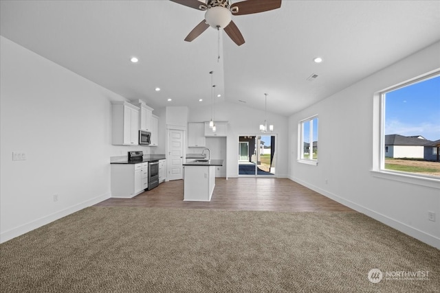 unfurnished living room with ceiling fan with notable chandelier, sink, dark wood-type flooring, and vaulted ceiling