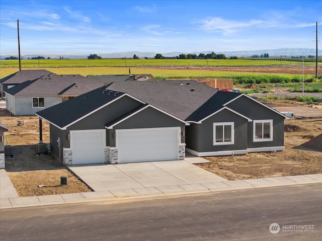 view of front of home featuring a garage, a rural view, and central AC