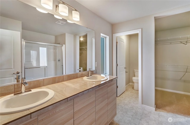 bathroom featuring vanity, toilet, and a shower with door