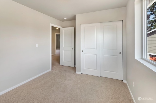 unfurnished bedroom featuring light carpet and a closet