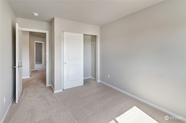 unfurnished bedroom with light carpet and a closet