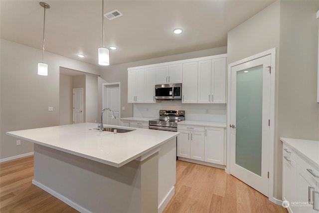 kitchen featuring a kitchen island with sink, sink, hanging light fixtures, and appliances with stainless steel finishes