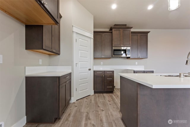 kitchen with light wood-type flooring, dark brown cabinetry, and sink