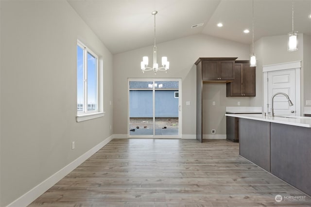 kitchen featuring pendant lighting, a notable chandelier, dark brown cabinets, and sink