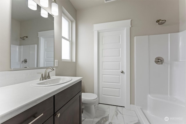 bathroom featuring a shower, vanity, and toilet