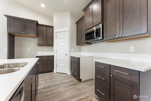 kitchen featuring dark brown cabinets, light hardwood / wood-style flooring, stainless steel appliances, and lofted ceiling