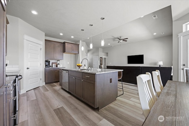 kitchen featuring sink, light stone countertops, light hardwood / wood-style floors, and an island with sink