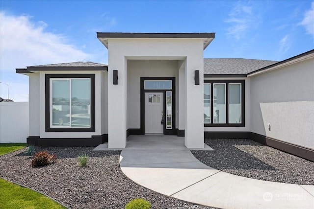 doorway to property with a shingled roof and stucco siding