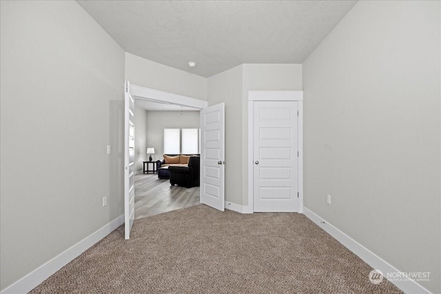 unfurnished bedroom with a textured ceiling, carpet, and baseboards