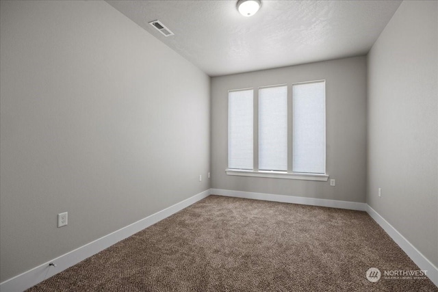 empty room featuring carpet flooring, visible vents, baseboards, and a textured ceiling