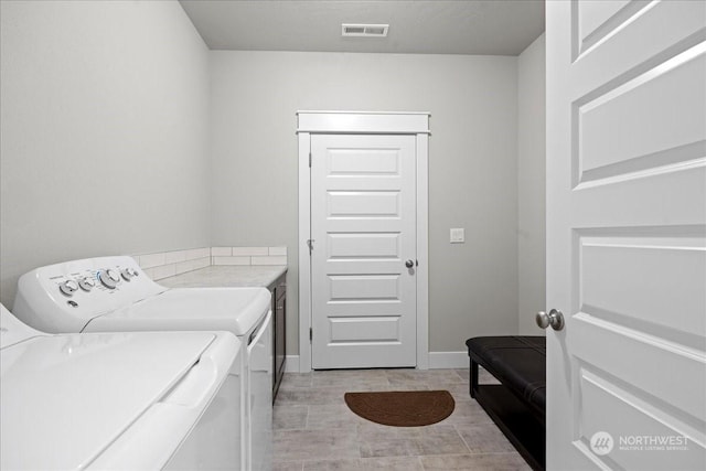 laundry area with laundry area, washing machine and dryer, visible vents, and baseboards