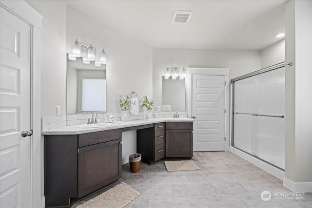 full bath featuring a stall shower, visible vents, a sink, and double vanity