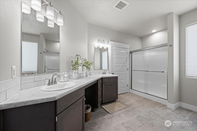 bathroom featuring double vanity, a sink, visible vents, and a shower stall