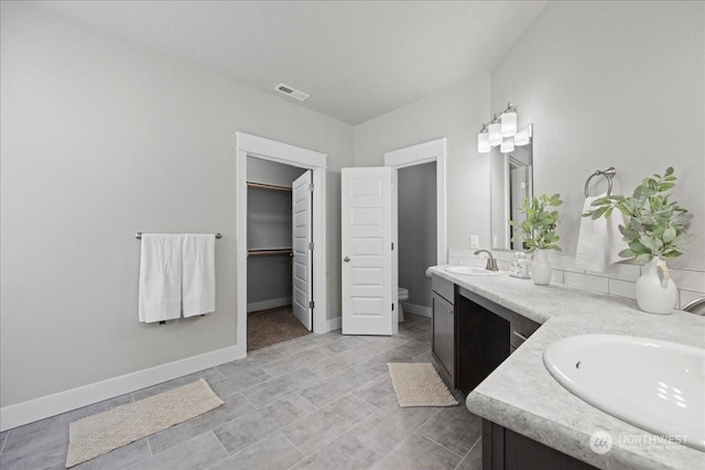 bathroom featuring toilet, double vanity, visible vents, and a sink