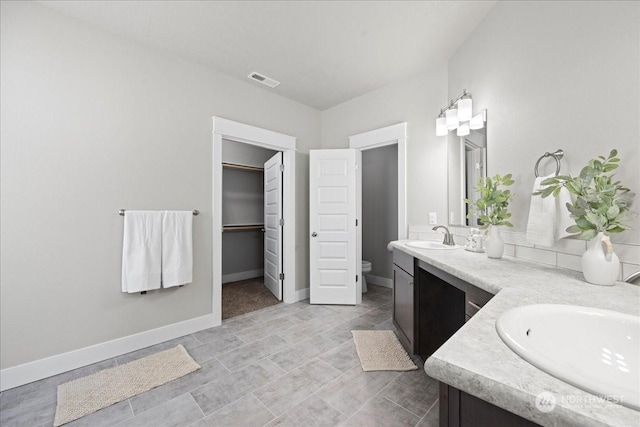 bathroom featuring visible vents, double vanity, a sink, and toilet