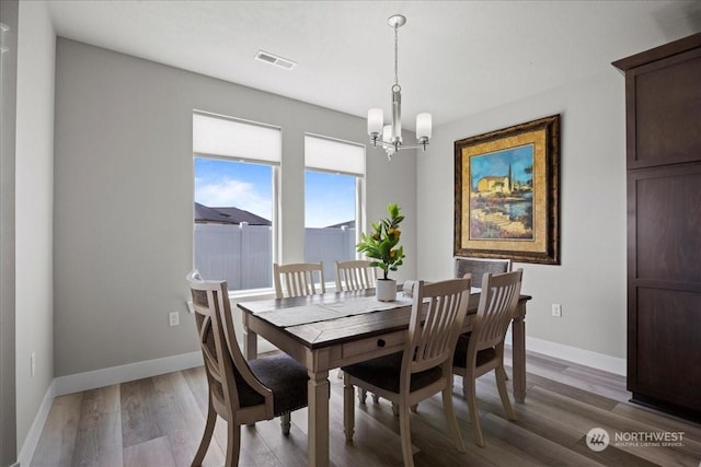 dining area featuring baseboards, a notable chandelier, and light wood finished floors