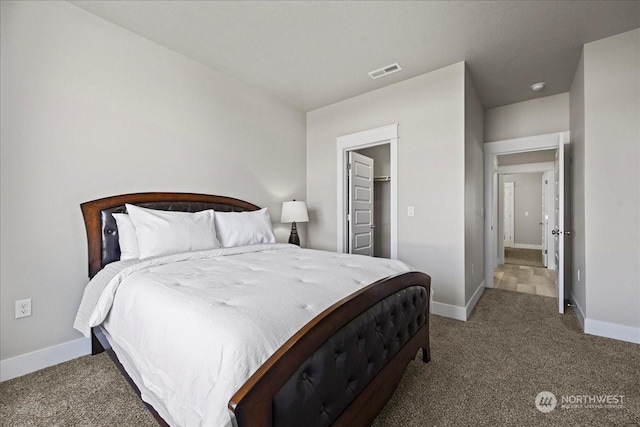 bedroom featuring carpet floors, a walk in closet, visible vents, and baseboards