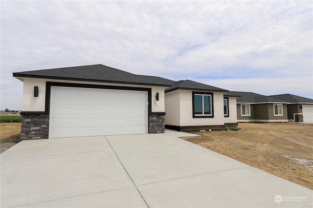 prairie-style house with a garage, stone siding, concrete driveway, and stucco siding