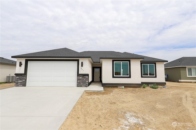 prairie-style house with stucco siding, a shingled roof, concrete driveway, an attached garage, and stone siding