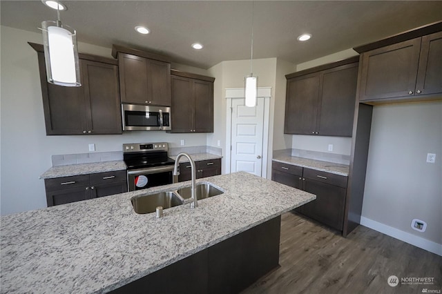 kitchen with stainless steel appliances, dark wood-style flooring, a sink, dark brown cabinets, and decorative light fixtures