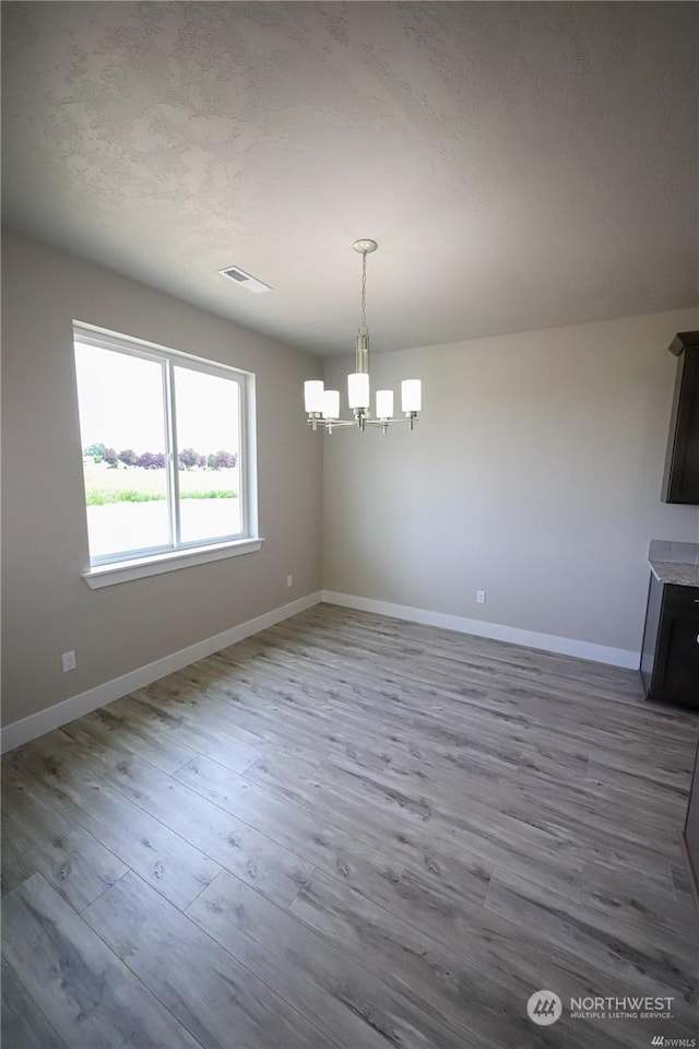 unfurnished dining area featuring wood finished floors, visible vents, and baseboards