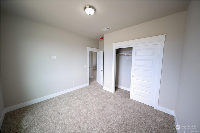 unfurnished bedroom with a closet, visible vents, light carpet, and baseboards