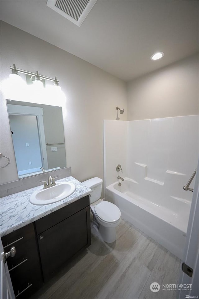 full bath featuring visible vents, toilet, washtub / shower combination, vanity, and wood finished floors