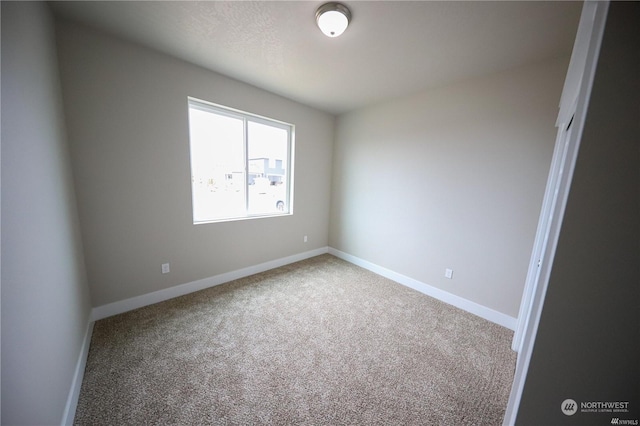 unfurnished room with carpet and baseboards