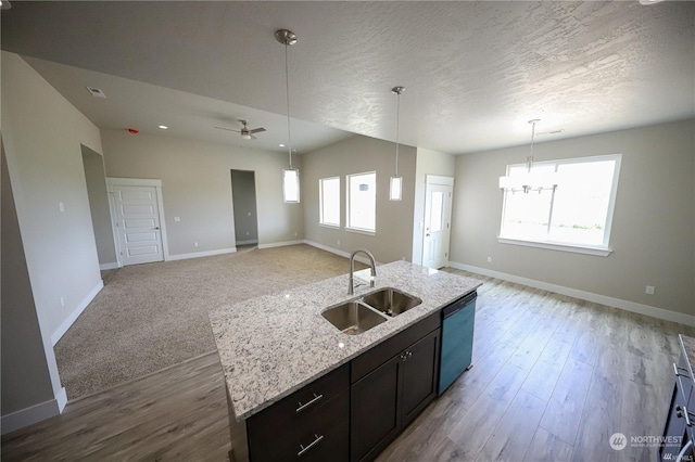 kitchen featuring open floor plan, dishwashing machine, a sink, and baseboards