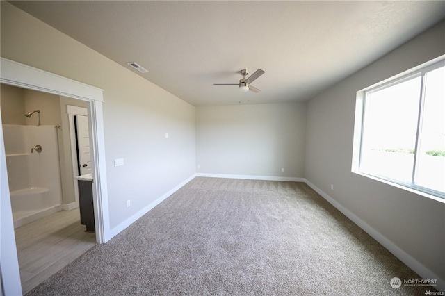 spare room with ceiling fan, light carpet, visible vents, and baseboards