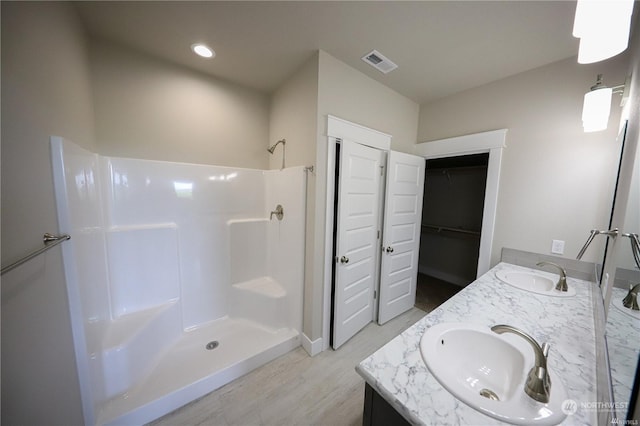 full bath featuring a shower, visible vents, a sink, and double vanity