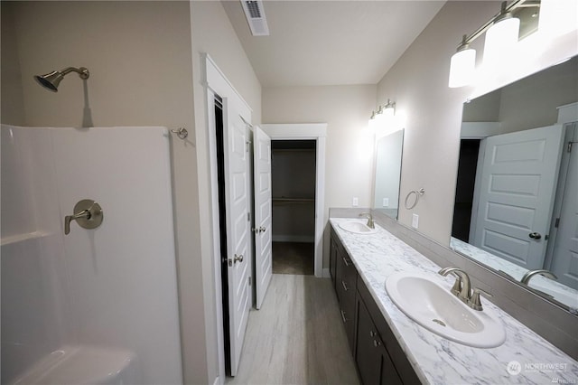 full bathroom featuring double vanity, visible vents, a shower, and a sink