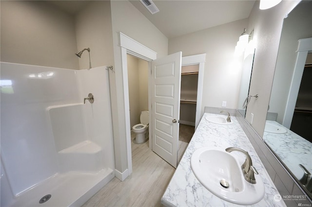 full bath with toilet, a stall shower, visible vents, and a sink