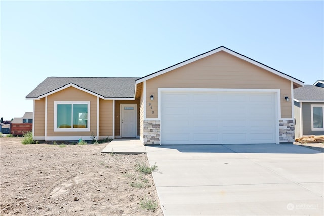 view of front of home featuring an attached garage, stone siding, driveway, and roof with shingles