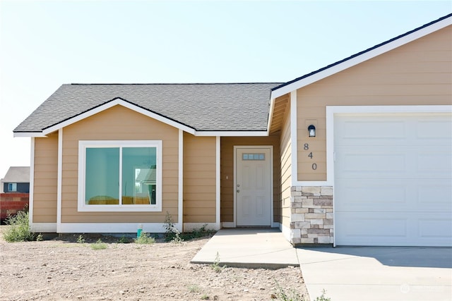 view of front of house featuring an attached garage and roof with shingles