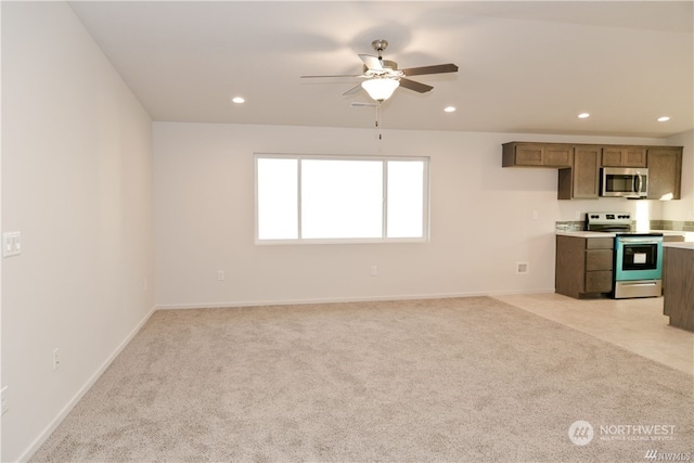 kitchen with stainless steel appliances, recessed lighting, light countertops, light colored carpet, and brown cabinetry